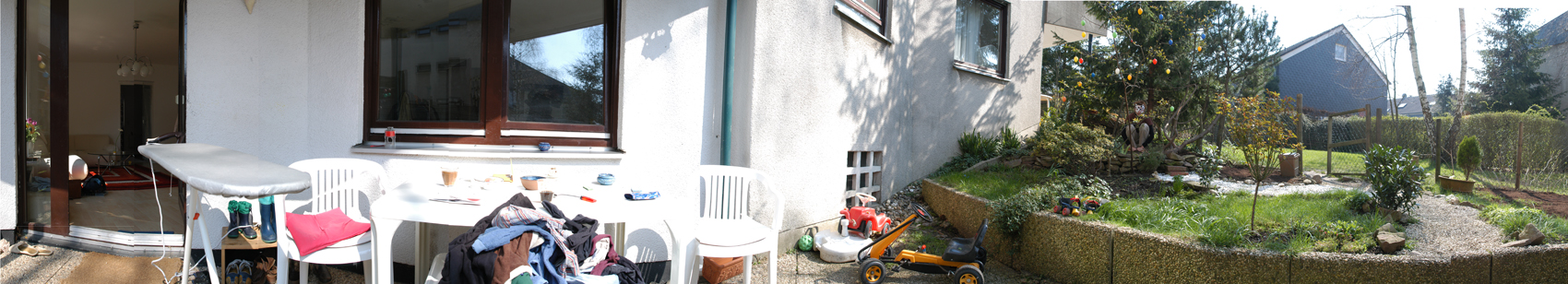 the cat-performer showing/hiding herself in a house garden with clothes, plants and other garden objects