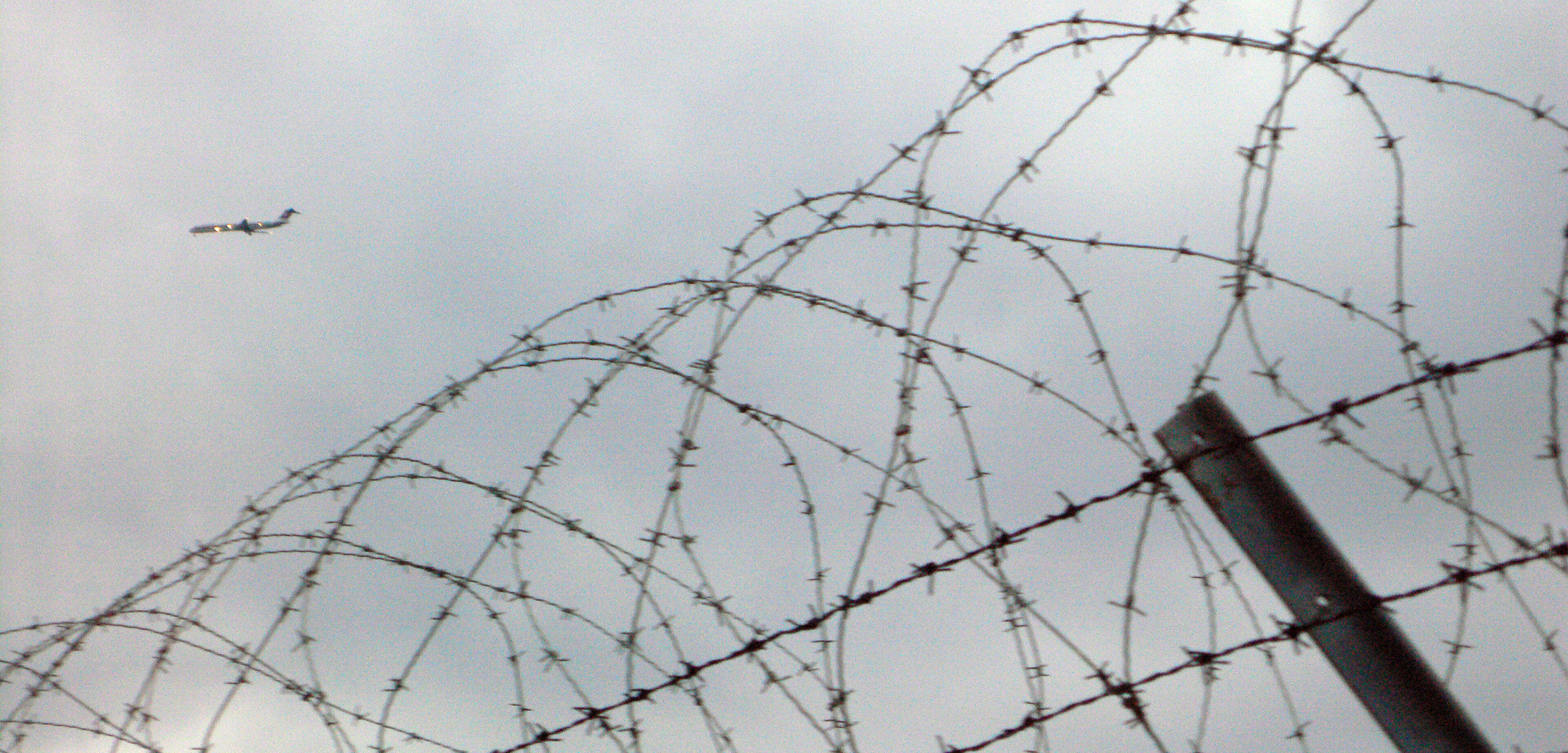 an airbus flying above a barbed wire